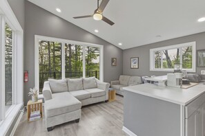 A modern living room with a sectional sofa, a dining area, and a kitchen island. - Lily Pad Hideaway on 19 Acres (Nimitz)