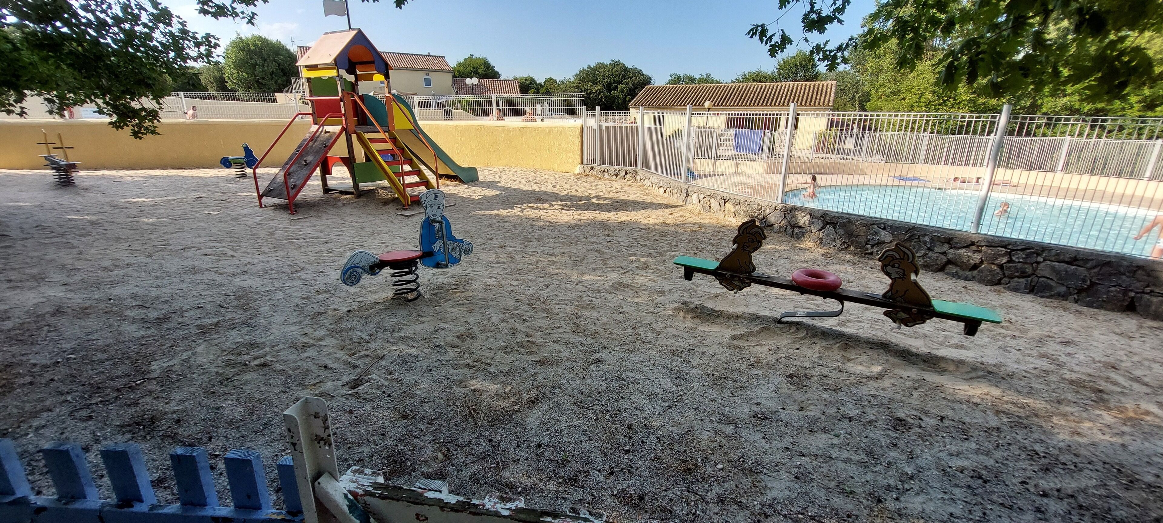 Un parque infantil con tobogán, columpios y sube y baja.