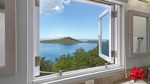 Ein Badezimmer mit einem großen Fenster mit Blick auf einen See und eine entfernte Insel.