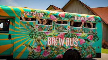 Ein farbenfroher Bus mit tropischen Motiven und dem Text 'BREW BUS' und 'TCBREWBUS.COM'.