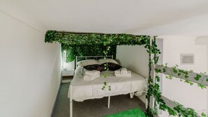 A bed with white bedding, a mirror, and green foliage on the headboard and wall. - GuestHost - Comfortable Studio Apartment MERCURIO - Torino (Torino)