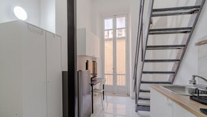 A compact kitchen with a refrigerator, a small dining table, and a sink. - GuestHost - Comfortable Studio Apartment MERCURIO - Torino (Torino)