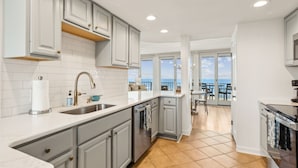 A modern kitchen with grey cabinets, white countertops, and a view to a balcony.