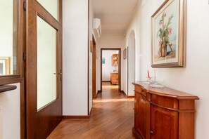 Un couloir avec un plancher en bois, une porte en bois, un meuble et un tableau encadré accroché au mur.