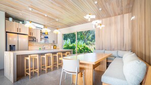A modern kitchen with wooden cabinets, a central island with stools, and pendant lighting.