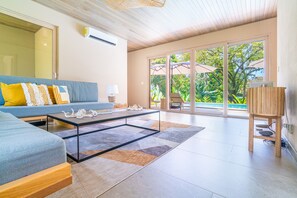 A modern living room with a sofa, coffee table, and a view of the outdoors.