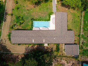 Vue aérienne d’une propriété comprenant un grand bâtiment rectangulaire, une piscine et de nombreux espaces verts.