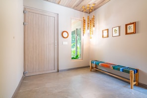 A hallway with a wooden door, a bench, and framed pictures on the wall. - Chalet Tropical by Pura Villas (Uvita)
