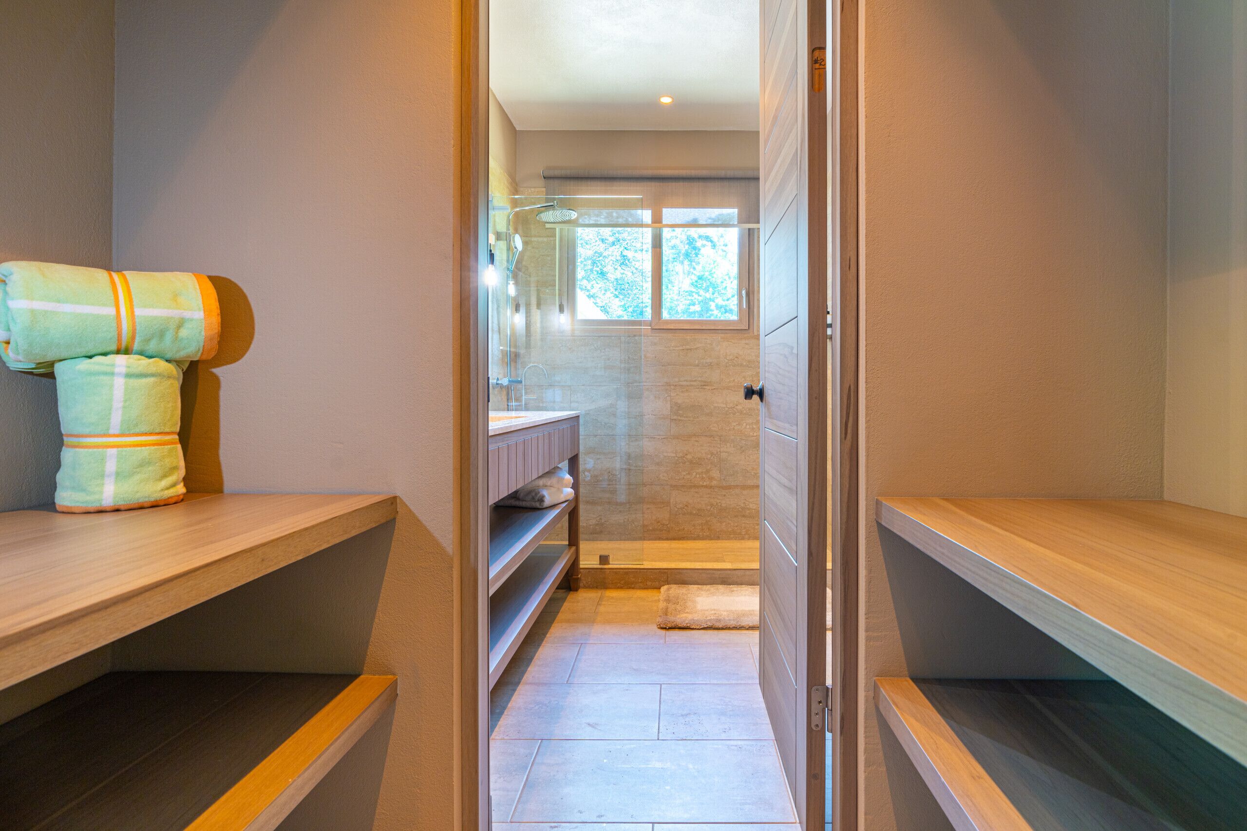 Une salle de bain moderne avec une douche à parois de verre, un meuble-lavabo en bois et un porte-serviettes.