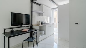 A modern kitchen with a TV, a dining area with a chair, and a sliding door leading to an outdoor area. - GuestHost - Comfortable Studio Apartment VENERE - Torino (Torino)