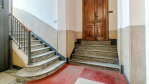 A staircase with a wooden door at the top, a metal railing, and a red carpet. - GuestHost - Comfortable Studio Apartment VENERE - Torino (Torino)
