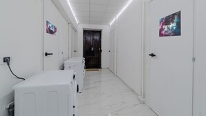 A hallway with white walls, a tiled floor, and a door at the end. - GuestHost - Comfortable Studio Apartment VENERE - Torino (Torino)