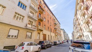 A multi-story residential building with balconies, parked cars, and a clear sky. - GuestHost - Comfortable Studio Apartment VENERE - Torino (Torino)