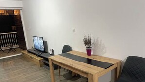 Un comedor moderno con una mesa y sillas de madera, un televisor y una planta en maceta.