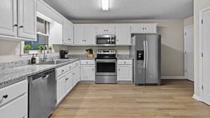 A modern kitchen with white cabinets, stainless steel appliances, and a granite countertop.