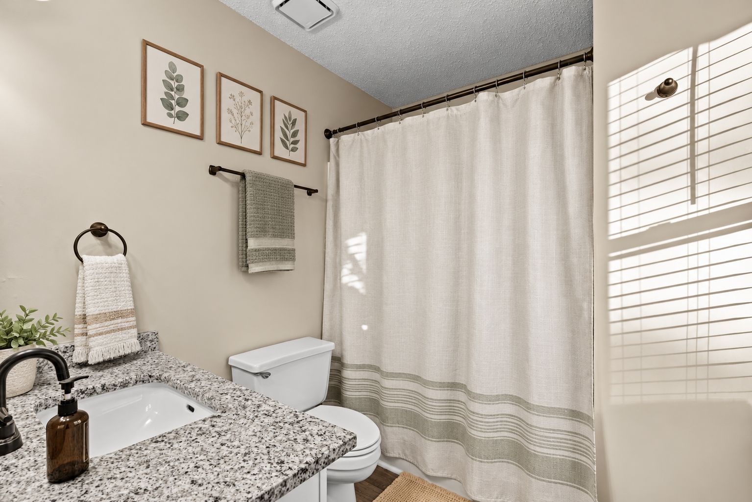 A bathroom with a granite countertop sink, a toilet, and a shower curtain.