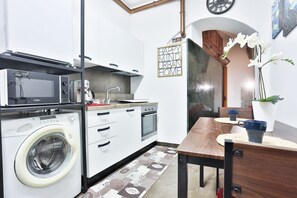 A compact kitchen with a washing machine, microwave, and oven.