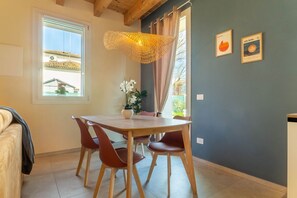 Un comedor con una mesa y sillas de madera, una lámpara colgante y una ventana con cortinas.