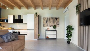 A modern living space with a kitchen, a sofa, a TV, and a wall-mounted plant. - GuestHost - Oasis of the Knight! (Ferrara)
