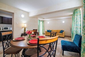 A dining area with a round table, chairs, and a kitchen in the background.