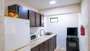 A compact kitchen with a white refrigerator, a microwave, a stove, and a sink. - Barbadian Charm: Boutique Stay Steps from Beaches (Oistins)