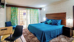 A bedroom with a large bed, a desk, a chair, and a TV. - Poolside Studio Near Dover & Turtle Beach w/ Pool (Oistins)