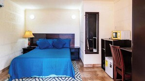 A bedroom with a bed, bedside tables, a lamp, a microwave, a chair, and a small refrigerator. - 5 Min to Beaches with Poolside Bar and Spa (Oistins)
