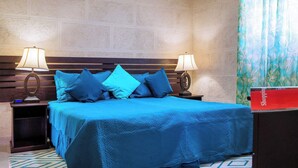 A hotel room with a large bed, two bedside tables with lamps, a wooden headboard, and a brick-patterned wall. - Steps to the Beach with Pool, Spa and Swim-up Bar (Oistins)