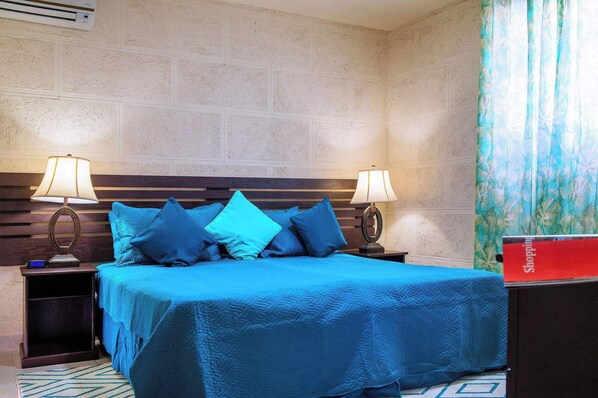 Habitación de hotel con una cama grande, dos mesitas de noche con lámparas, un cabecero de madera y una pared con diseño de ladrillo.
