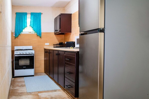 A compact kitchen with a stove, oven, microwave, and refrigerator.