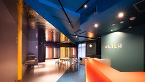 A modern interior with a reception desk, seating area, and a wall with a logo.