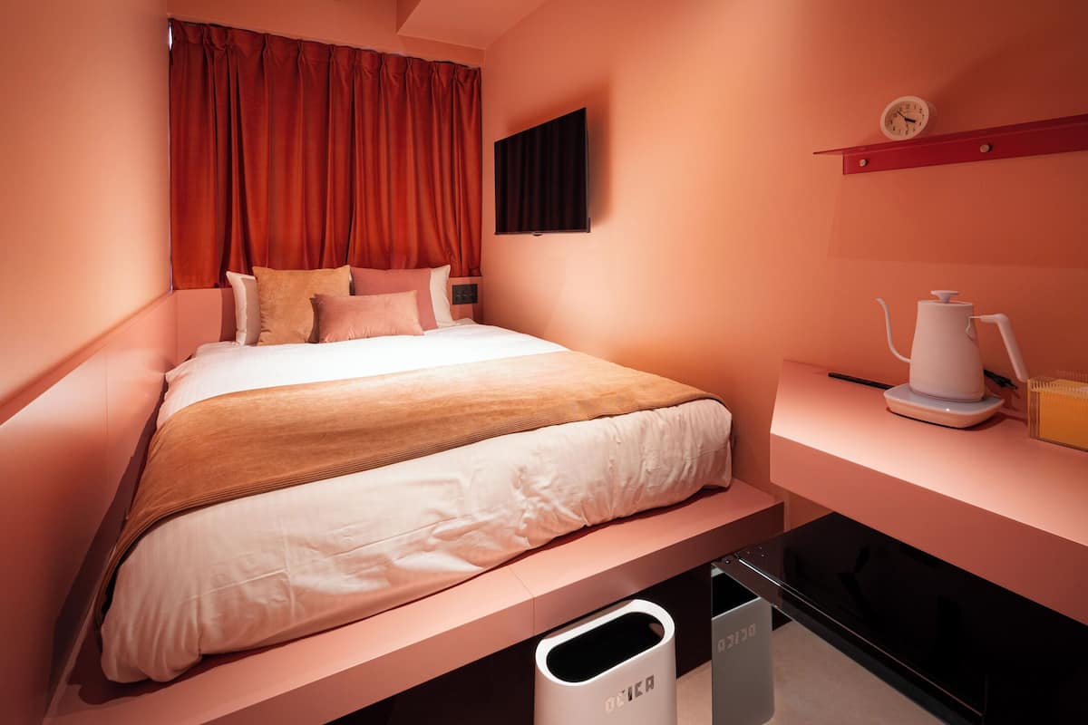 A neatly arranged hotel room with a bed, bedside table, and a small desk area.