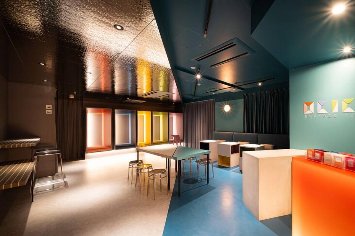 A modern interior with a reception desk, seating area, and a wall with geometric patterns.