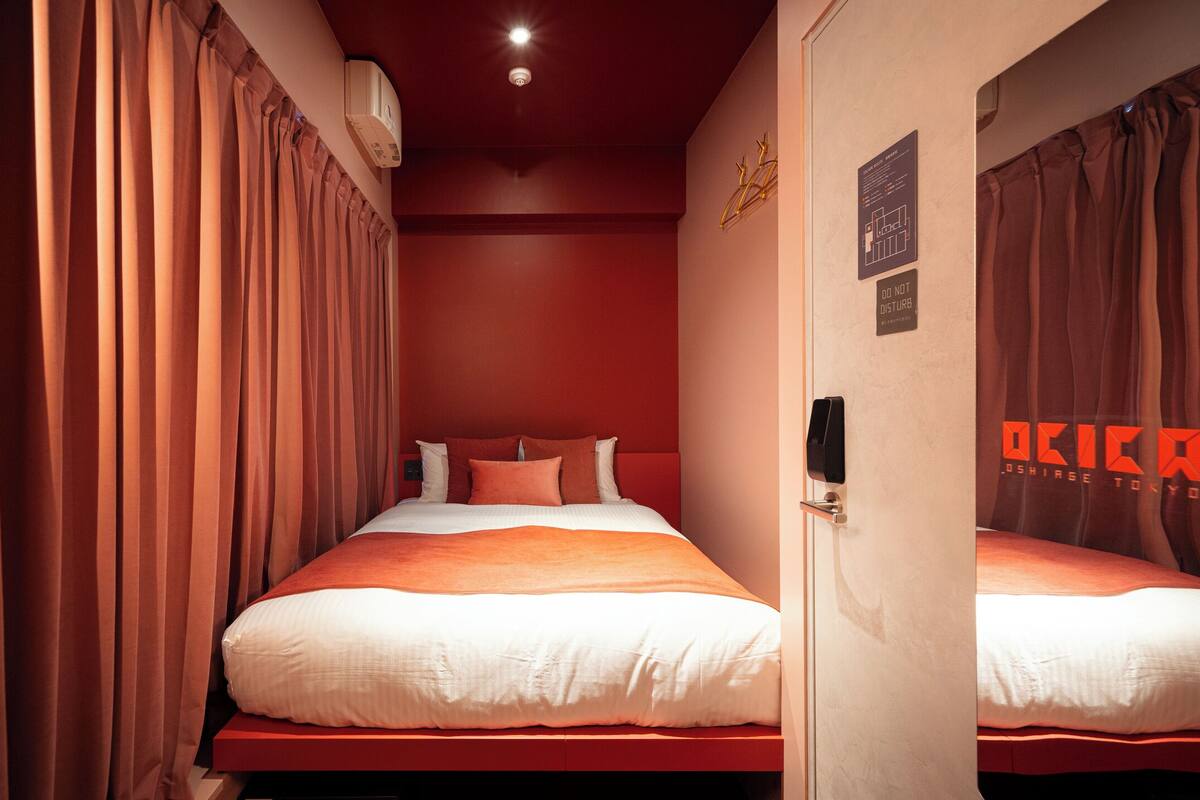 A hotel room with two beds, red walls, and curtains.