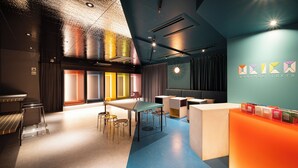 A modern hotel lobby with a reception desk, seating area, and a colorful wall design.