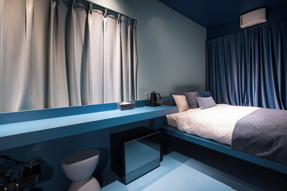 A modern bedroom with a bed, a desk, and a TV.