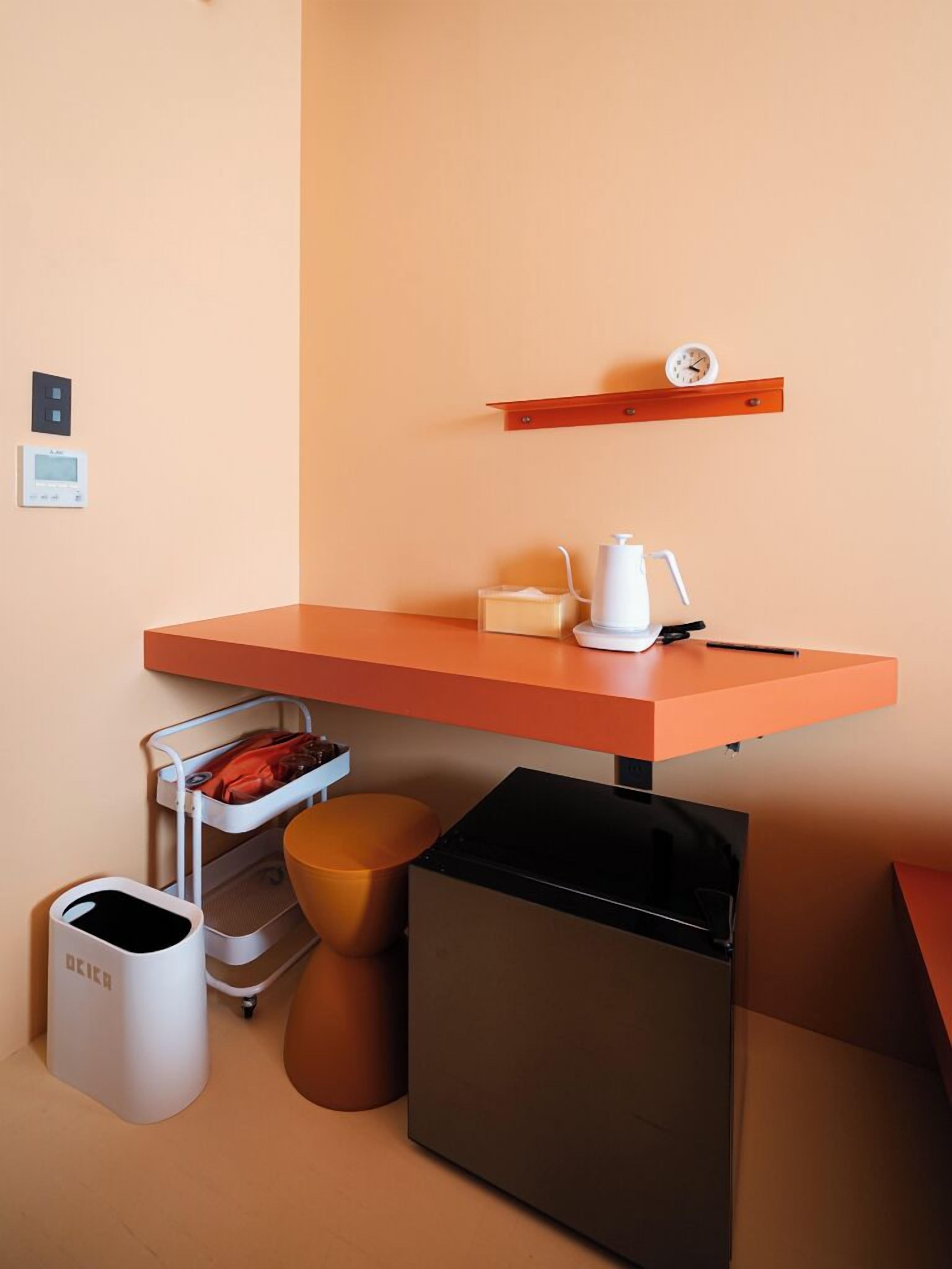 Eine kompakte Küchenzeile mit Arbeitsplatte, einer Kaffeemaschine, einem Mülleimer und einem kleinen Kühlschrank.