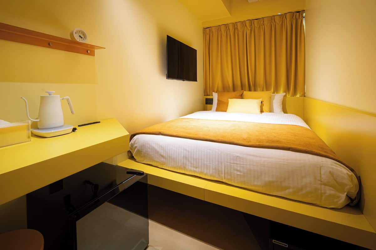 A hotel room with a bed, a desk, and a coffee maker.