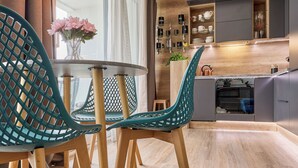 Una cocina moderna con armarios de madera, horno empotrado y zona de comedor con sillas color turquesa y una mesa redonda.