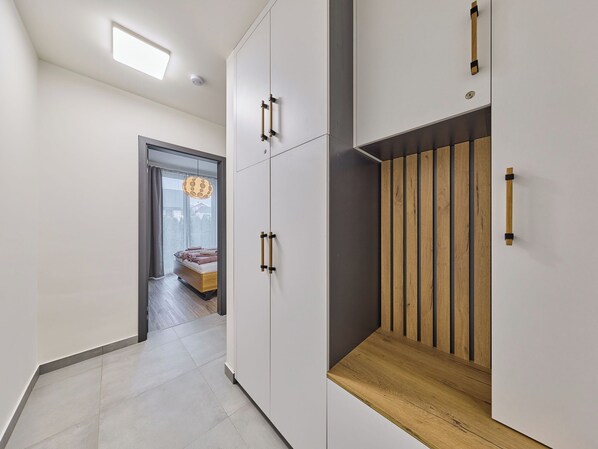 Un interior moderno con un pasillo que conduce a un dormitorio con cama y ventana.