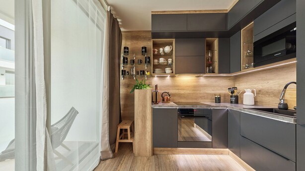 Una cocina moderna con armarios oscuros, encimera de madera y horno empotrado.