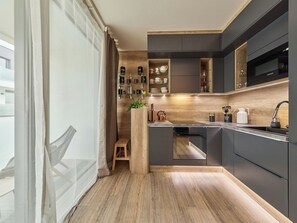 Una cocina moderna con armarios oscuros, encimera de madera y horno empotrado.