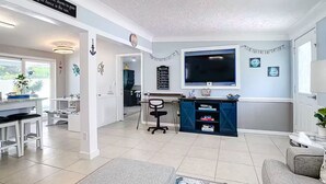 A spacious living area with a kitchen, dining area, and a TV mounted on the wall.