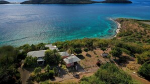 A coastal property with a paved driveway, a small building, and a beach.
