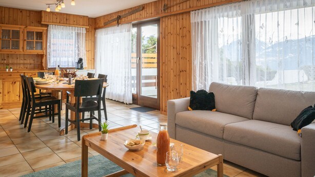 A cozy living room with a sofa, a coffee table, and a dining area with chairs and a table. - Austral 105 by Interhome (Ovronnaz)