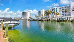 A marina with boats docked, a clear blue sky, and a multi-story hotel with balconies and palm trees. - Destin Harbor Views & Access to Boat Dock! CP6 (Destin)