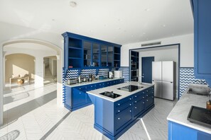 A modern kitchen with blue cabinetry, a central island, and a herringbone floor pattern. - Villa Stunning view on the sea of Naples with private pool and beach access (San Montano)