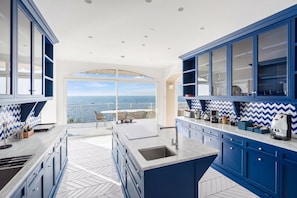 A modern kitchen with blue cabinets, a large island, and a view of the ocean. - Villa Stunning view on the sea of Naples with private pool and beach access (San Montano)