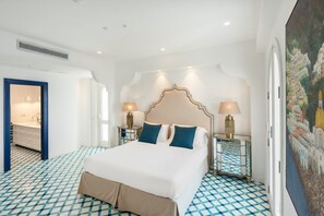 A hotel room with a large bed, two bedside lamps, a decorative headboard, and a patterned floor. - Villa Stunning view on the sea of Naples with private pool and beach access (San Montano)