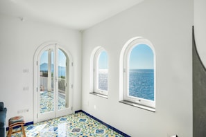 A room with a view of the sea, a patterned floor, and a door leading to an outdoor area. - Villa Stunning view on the sea of Naples with private pool and beach access (San Montano)